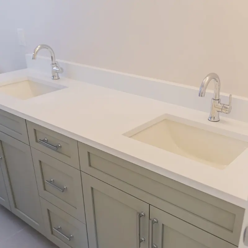 Integrated Matte White Bathroom Vanity Tops and Sinks on sage green cabinetry with chrome faucets.