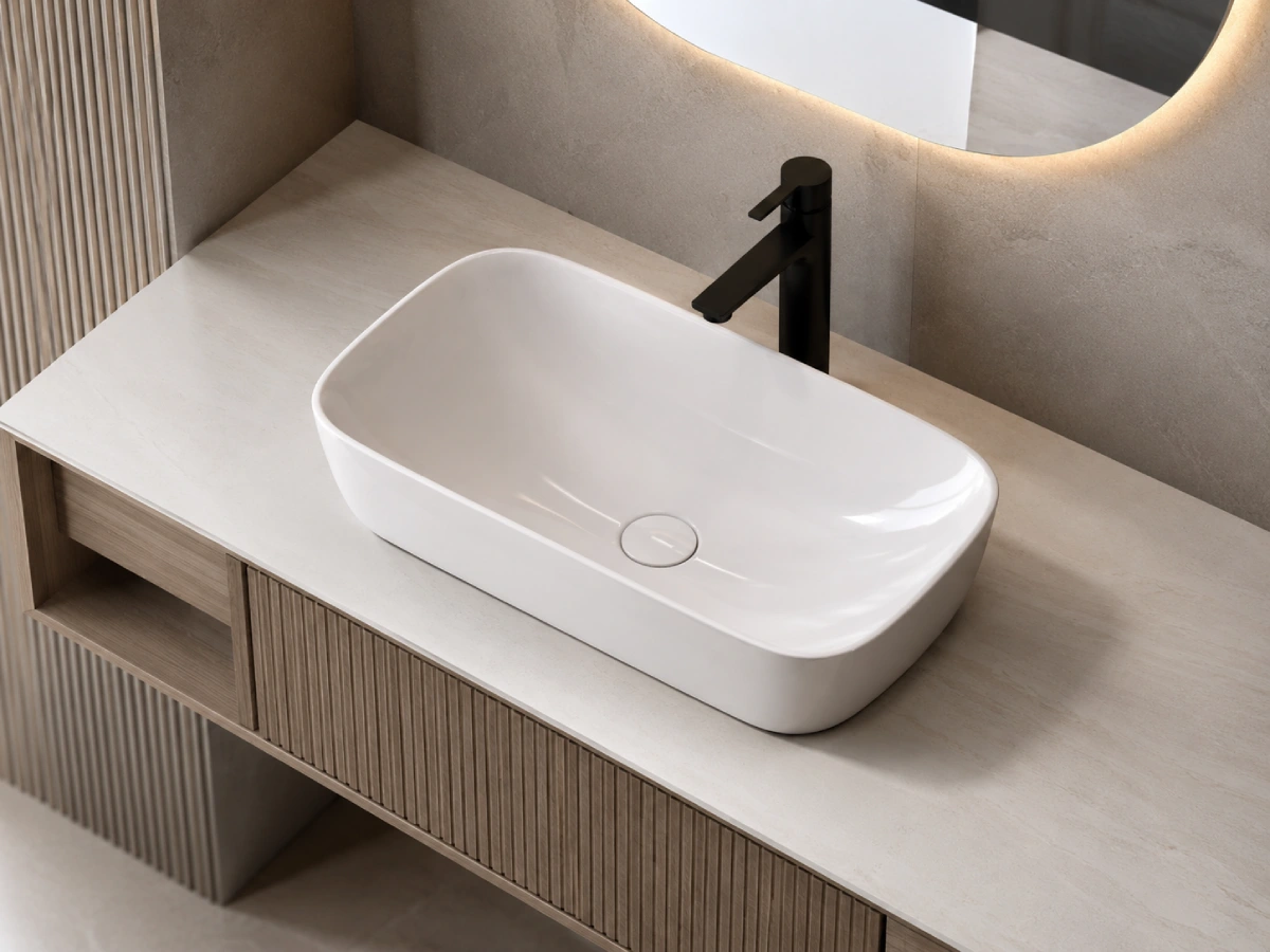 Modern white ceramic bathroom sink on a vanity with black faucet and illuminated mirror for bathroom project selection